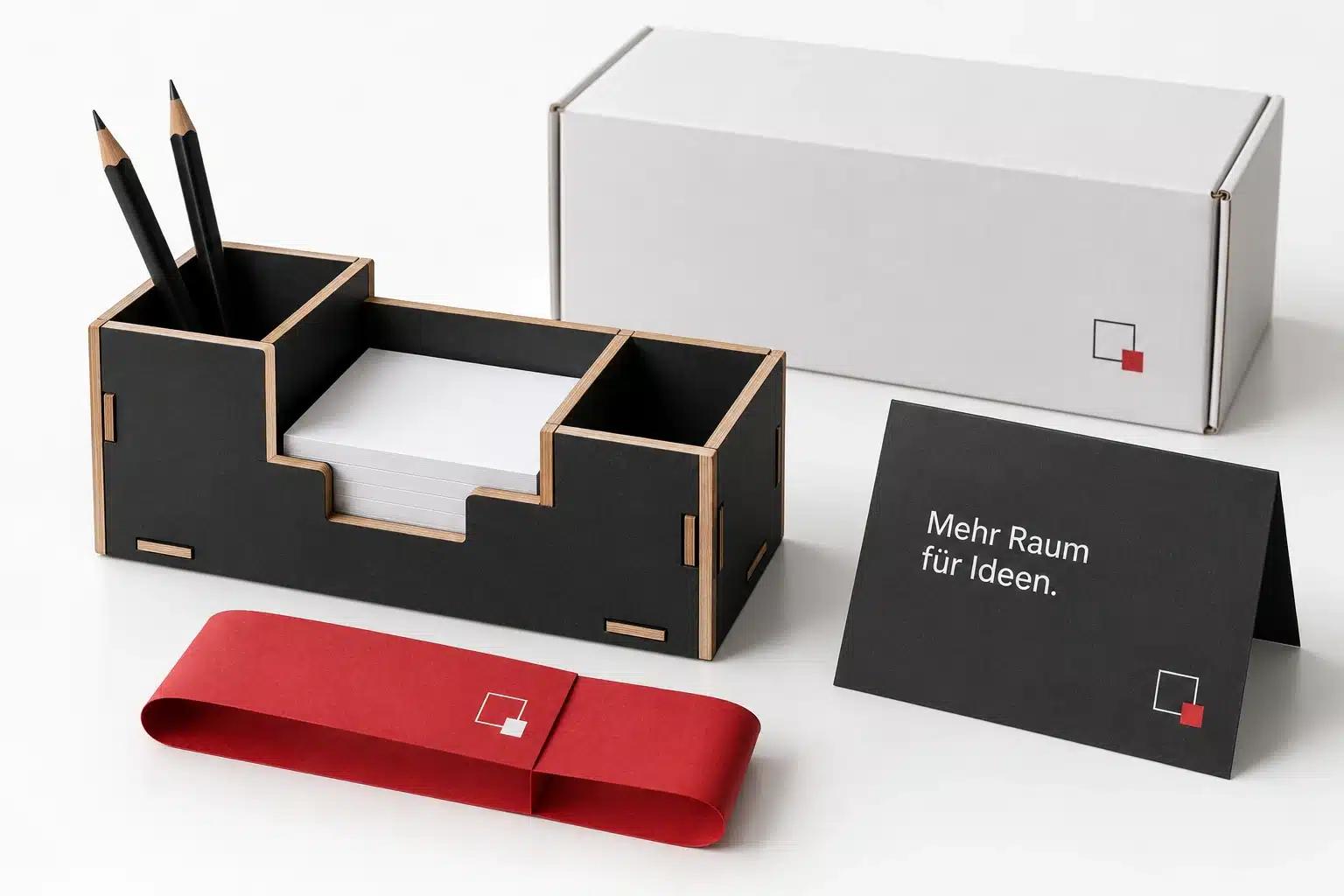 Weihnachtsmailings: Geschenke, die zu Kunden passen 6 KI-Konzept eines kompakten schwarzen Schreibtisch-Organizers mit roter Banderole und passender Grußkarte