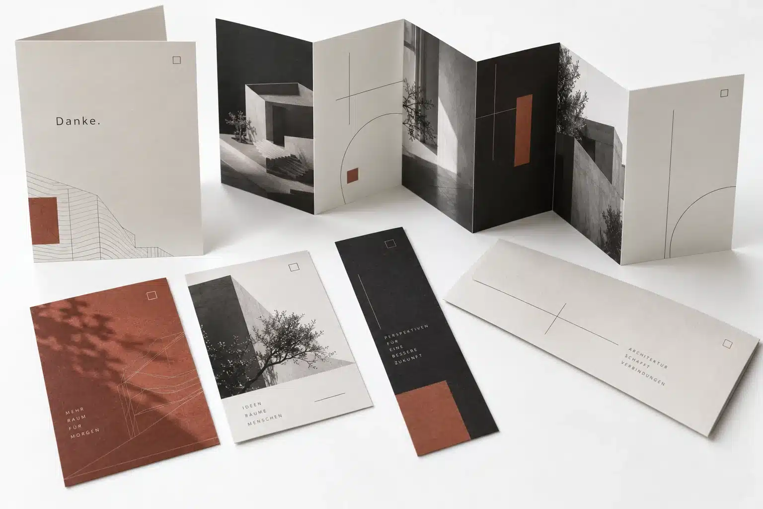 Weihnachtsmailings: Geschenke, die zu Kunden passen 2 KI-Konzept eines Architekturmailings mit Faltkarte, Lesezeichen, Bildkarten und Umschlag in Schwarz und Terrakotta